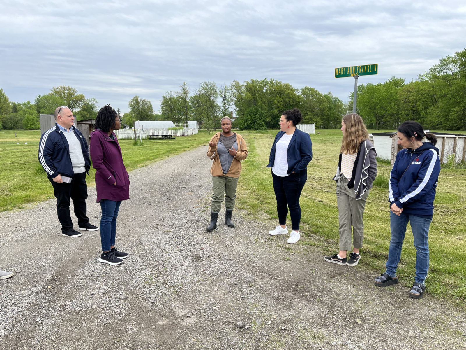 Representatives from several Akron area foundations and TNP employees look on as Christian Bennet-Mosley, healthy retail access coordinator from TNP, center, gives a tour of one of the community gardens. From left: John Garofalo, vice president of community investment, Akron Community Foundation; Bronlynn Thurman, GAR Foundation; Cristina Gonzalez-Alcala, Akron Community Foundation; Lydia Walls, AmeriCorps VISTA, TNP and Sevasti Tripoulas, community programs coordinator, TNP.